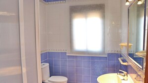 A bathroom with a toilet, sink, and mirror.