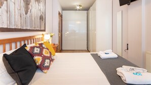 Een hotelkamer met een bed, een televisie, een kledingkast en een badkamer, zichtbaar door een geopende deur.