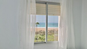 A room with a large window overlooking a beach. - Apartment in Conil amazing beach views (CONIL DE LA FRONTERA)