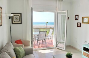 A living room with a sofa, a coffee table, and a balcony with a table and chairs.