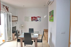 A dining area with a table, chairs, a fan, and a wall-mounted light fixture. - Apartment in town centre with terrace (CONIL DE LA FRONTERA)