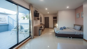 A modern bedroom with a bed, a desk, and a TV. There is a balcony with a chair and a table. - The Moon Night Hotel (Bangkok)