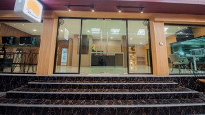 A hotel entrance with a reception desk, a staircase leading to the lobby, and a sign indicating the hotel name. - The Moon Night Hotel (Bangkok)