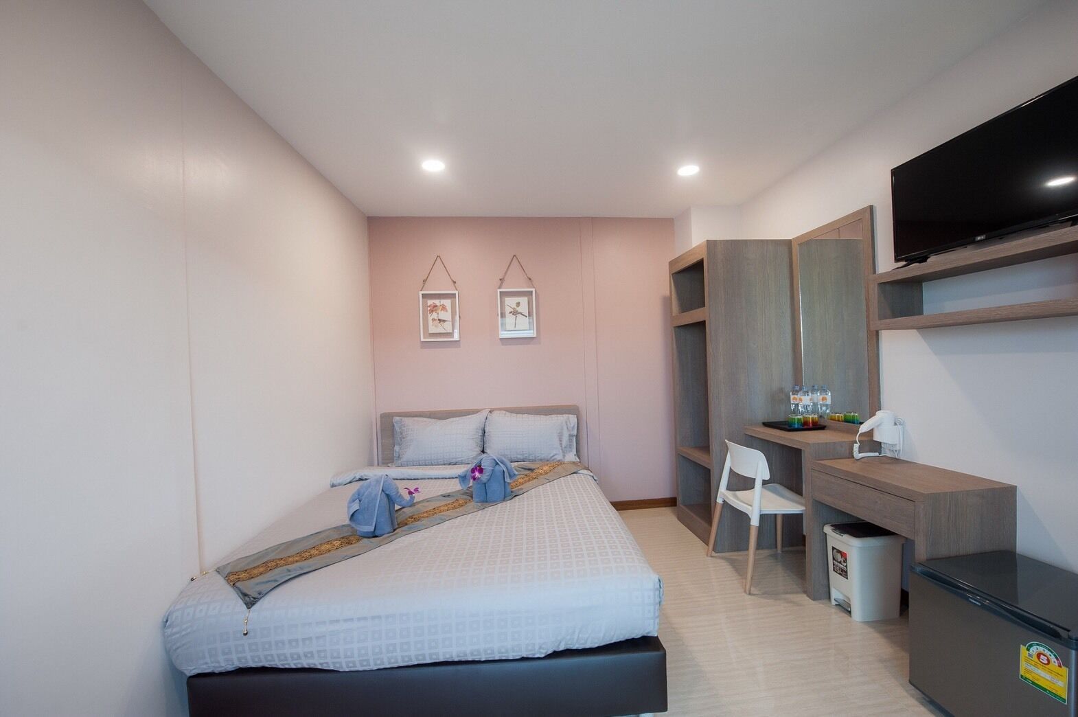 A bedroom with a bed, bedside table, chair, TV, and a desk with a chair.