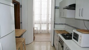 Una cocina con refrigerador, estufa, microondas y una mesa de madera.