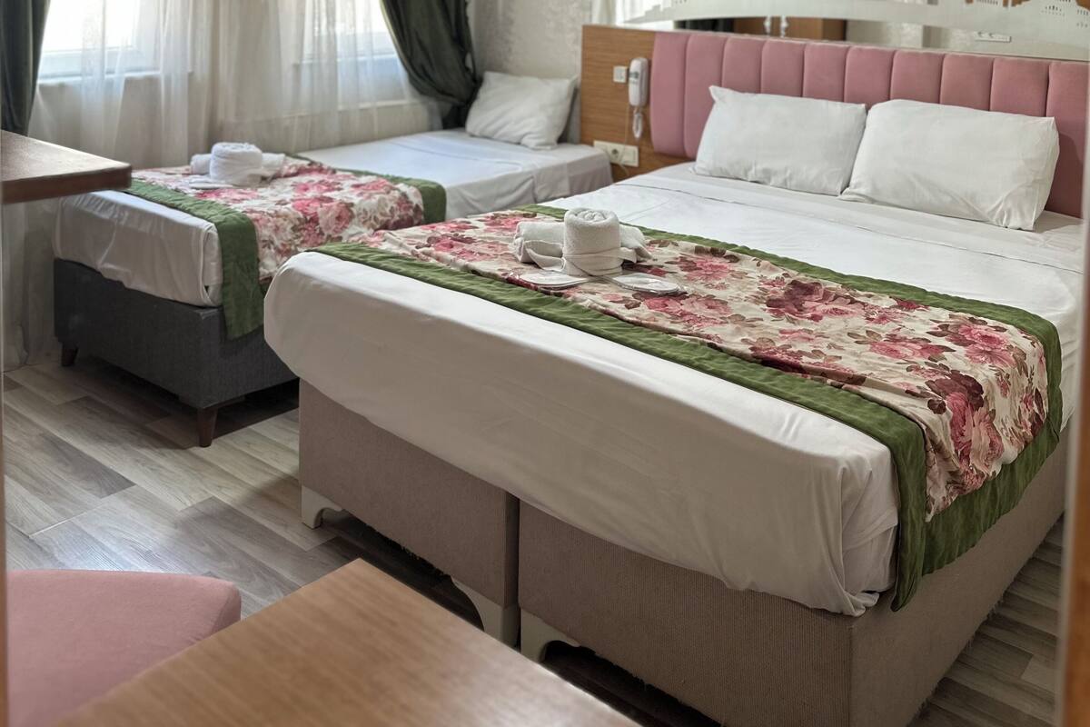 A hotel room with two beds, a desk, and a large mirror.