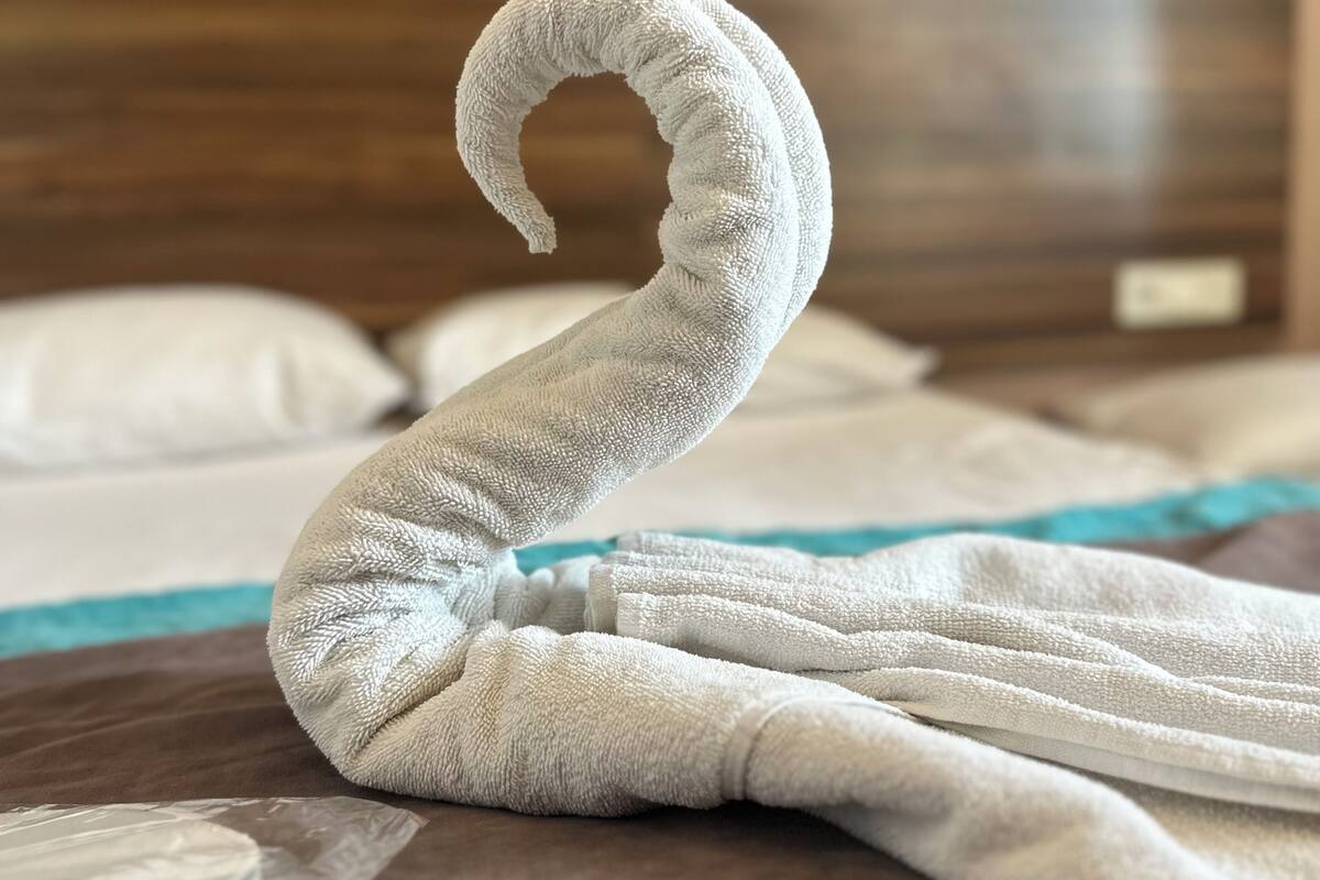 A neatly folded towel on a bed with a wooden headboard and two black lamps.