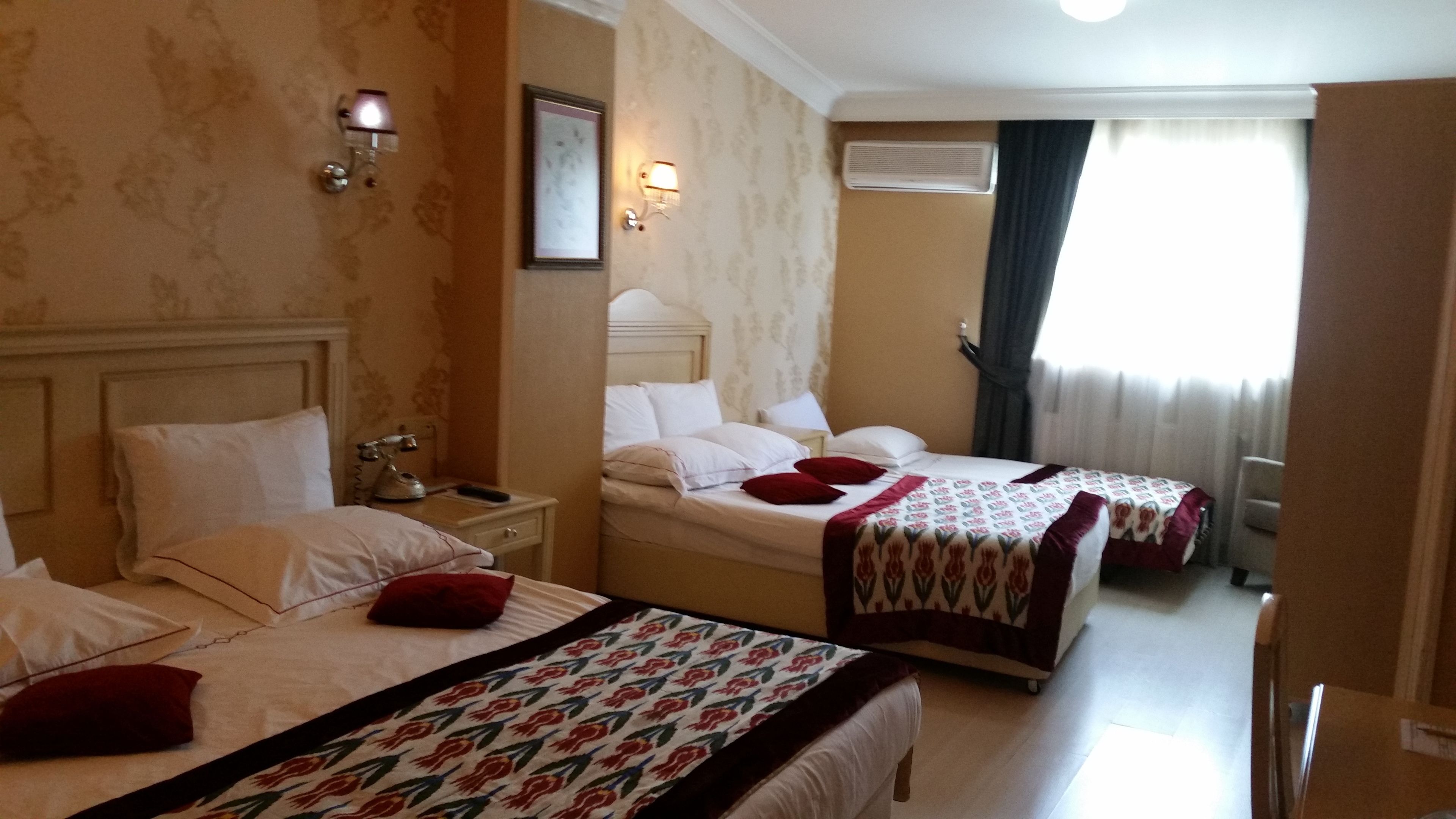A hotel room with two beds, a nightstand, a lamp, a framed picture, and an air conditioning unit.