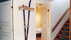 Ein Zimmer mit einem Bett, einer Holztreppe und einer Tür, an der Ski hängen.