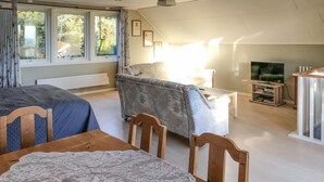 Ein gemütliches Wohnzimmer mit einer Couch, einem Fernseher und einem Tisch mit einer Spitzendecke.