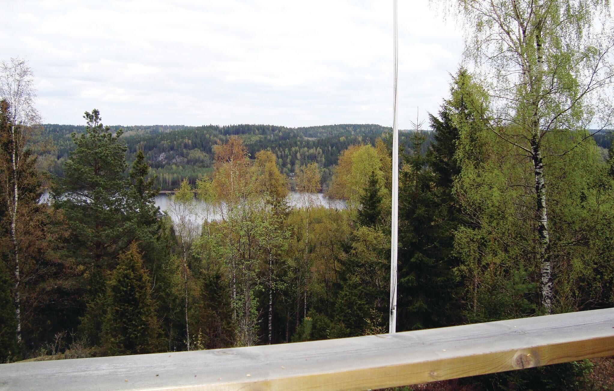 Une vue depuis un balcon donnant sur un lac entouré d’arbres.