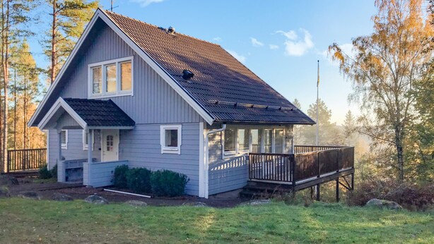 Ein zweistöckiges Haus mit überdachter Veranda und einer Terrasse.