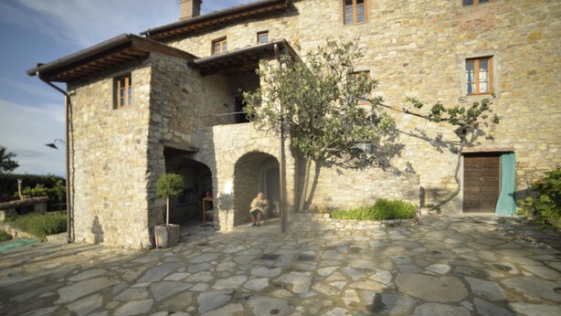 A stone building with a courtyard, arched entryway, and a tree.