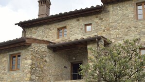 A stone building with a rustic charm, featuring arched doorways and a chimney.