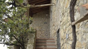 A stone staircase leading to a wooden door, with a number '23' sign on the wall.