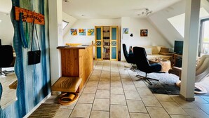 A spacious loft with a high ceiling, a wooden reception desk, a seating area with a sofa and chairs, a television, and a large window. - Vacation apartment Baum - Holiday apartment (Rechlin)