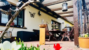 A patio area with a table and chairs, a potted plant, and a butterfly wall decoration. - Vacation apartment Baum - Holiday apartment (Rechlin)