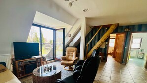 A living room with a TV, leather chairs, a coffee table, and a staircase. - Vacation apartment Baum - Holiday apartment (Rechlin)