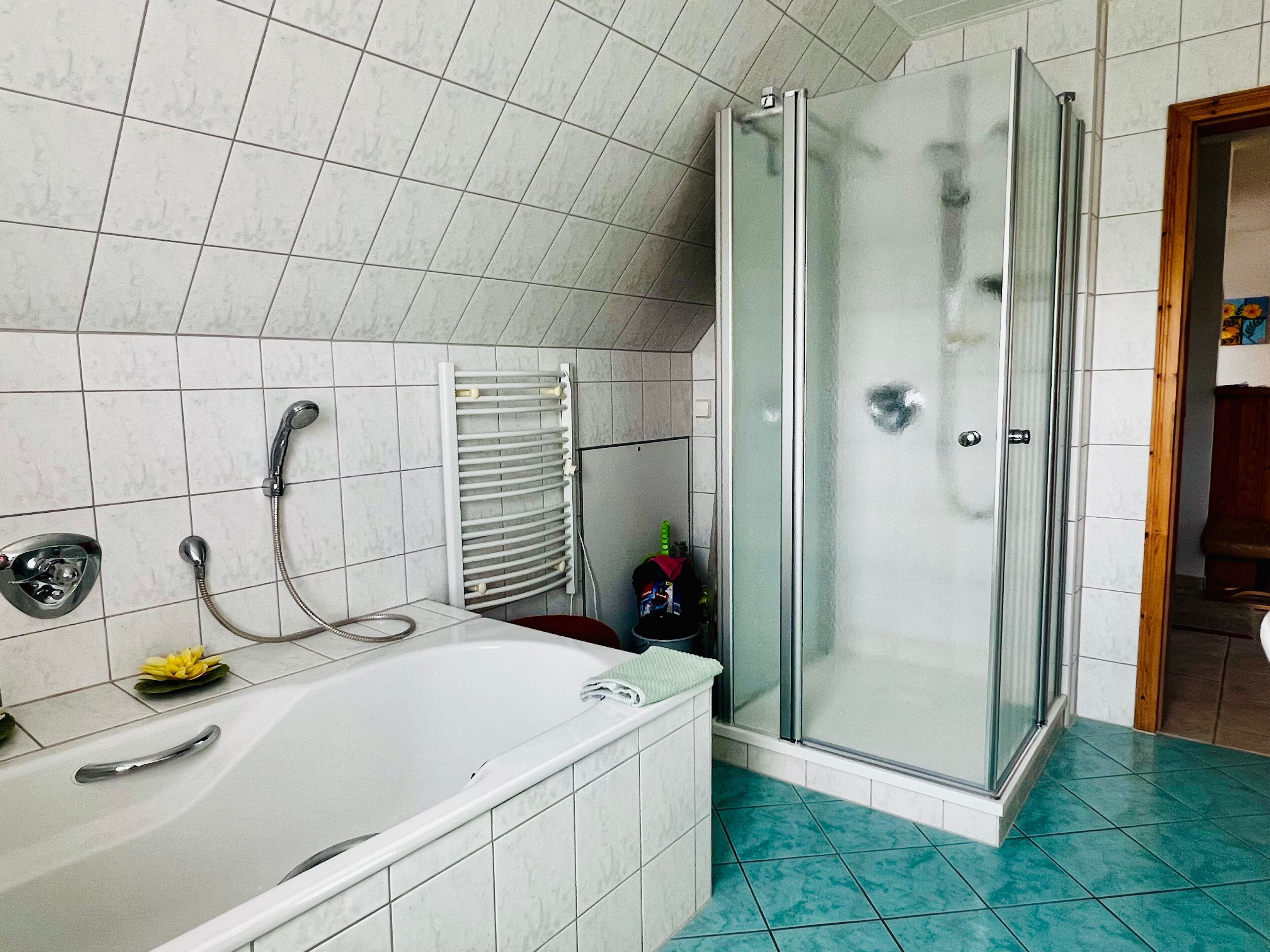 A bathroom with a bathtub, shower, and glass-enclosed shower stall.