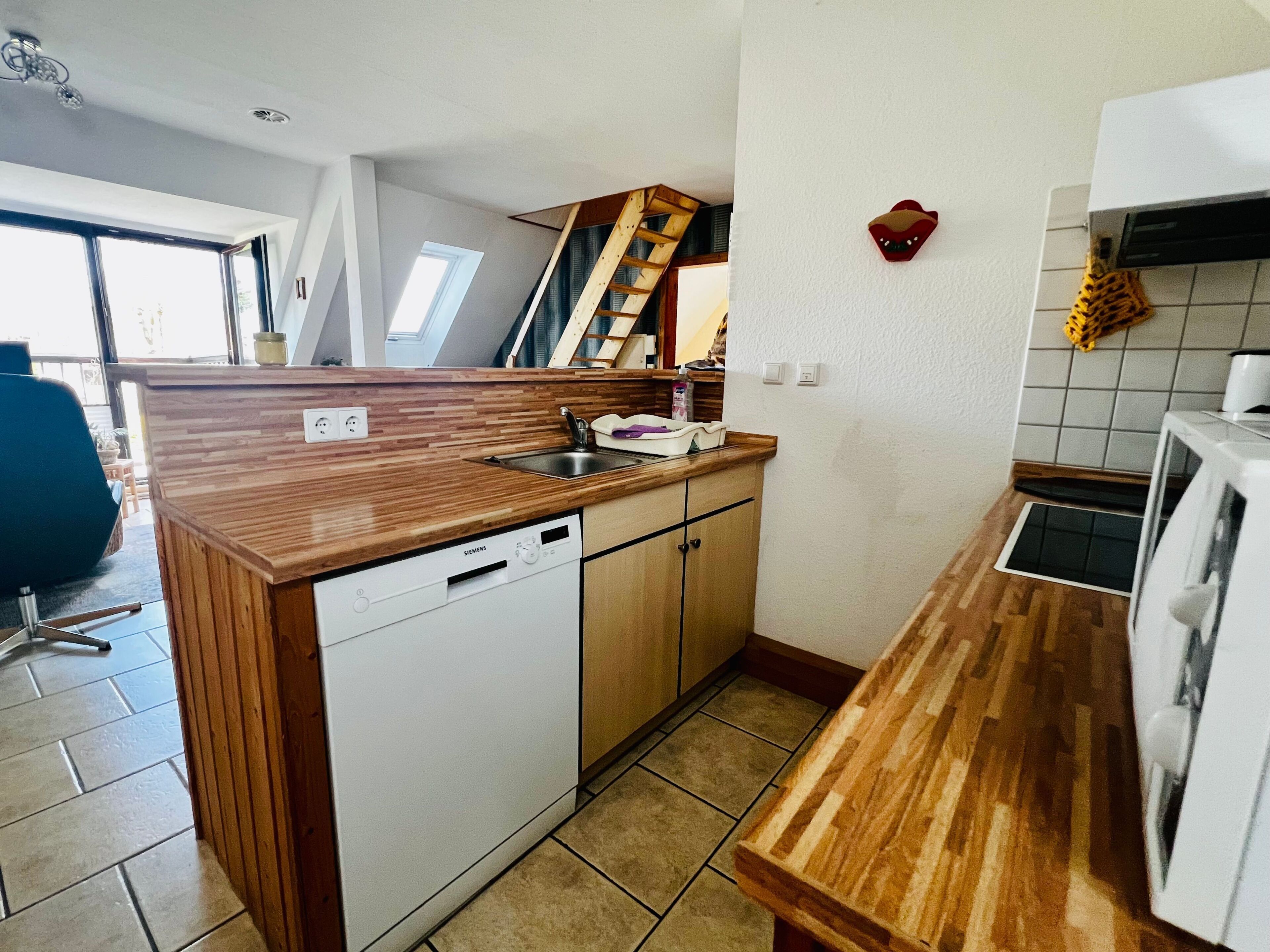 Eine kleine Küche mit Geschirrspüler, Holz Arbeitsplatte und einem Kühlschrank.