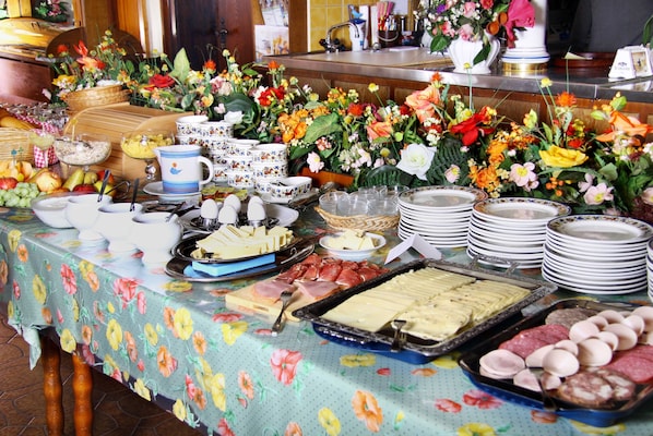 A buffet table with various food items and a floral arrangement.