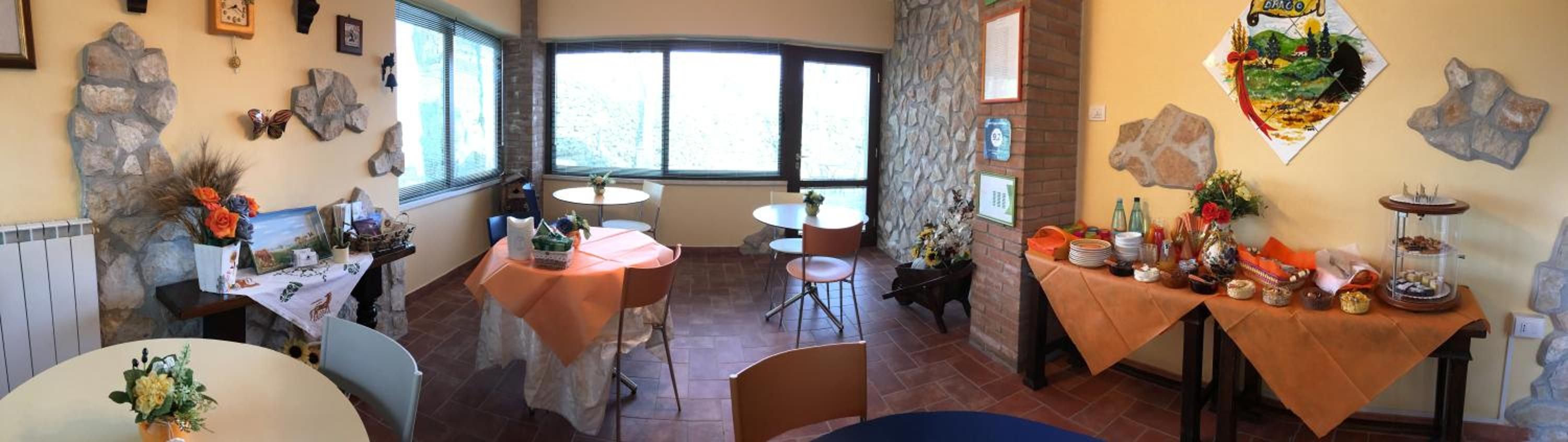 A dining area with round tables and chairs, stone wall decorations, and a view through large windows.