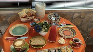 A breakfast table with various food items, plates, and a pitcher of juice. - Agriturismo Poggio del Drago (Manciano)