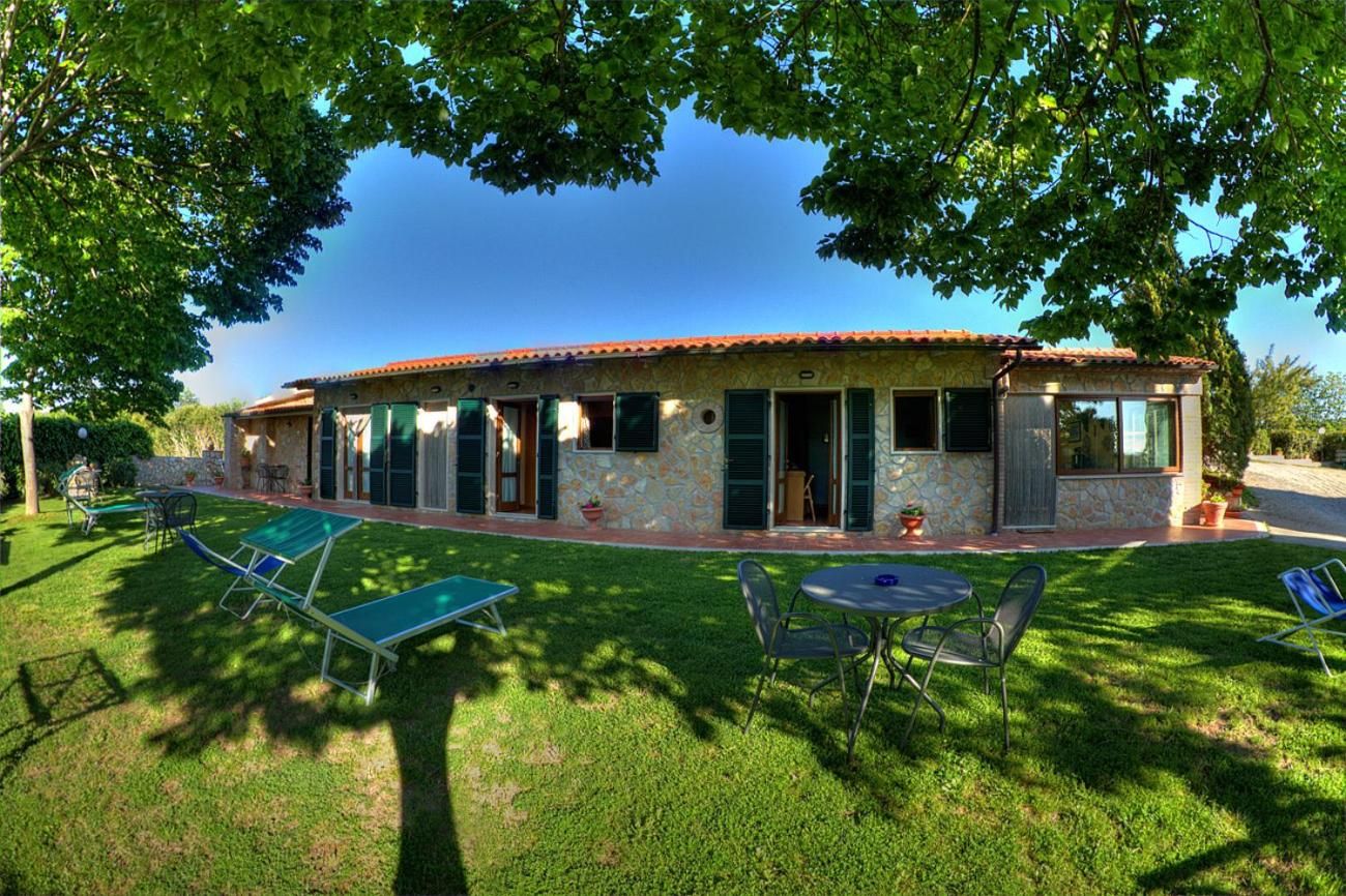 A house with a stone facade, green shutters, and a patio with outdoor furniture.
