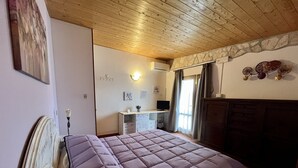 A bedroom with a bed, a desk, a chair, a TV, and a wardrobe. - Agriturismo Poggio del Drago (Manciano)