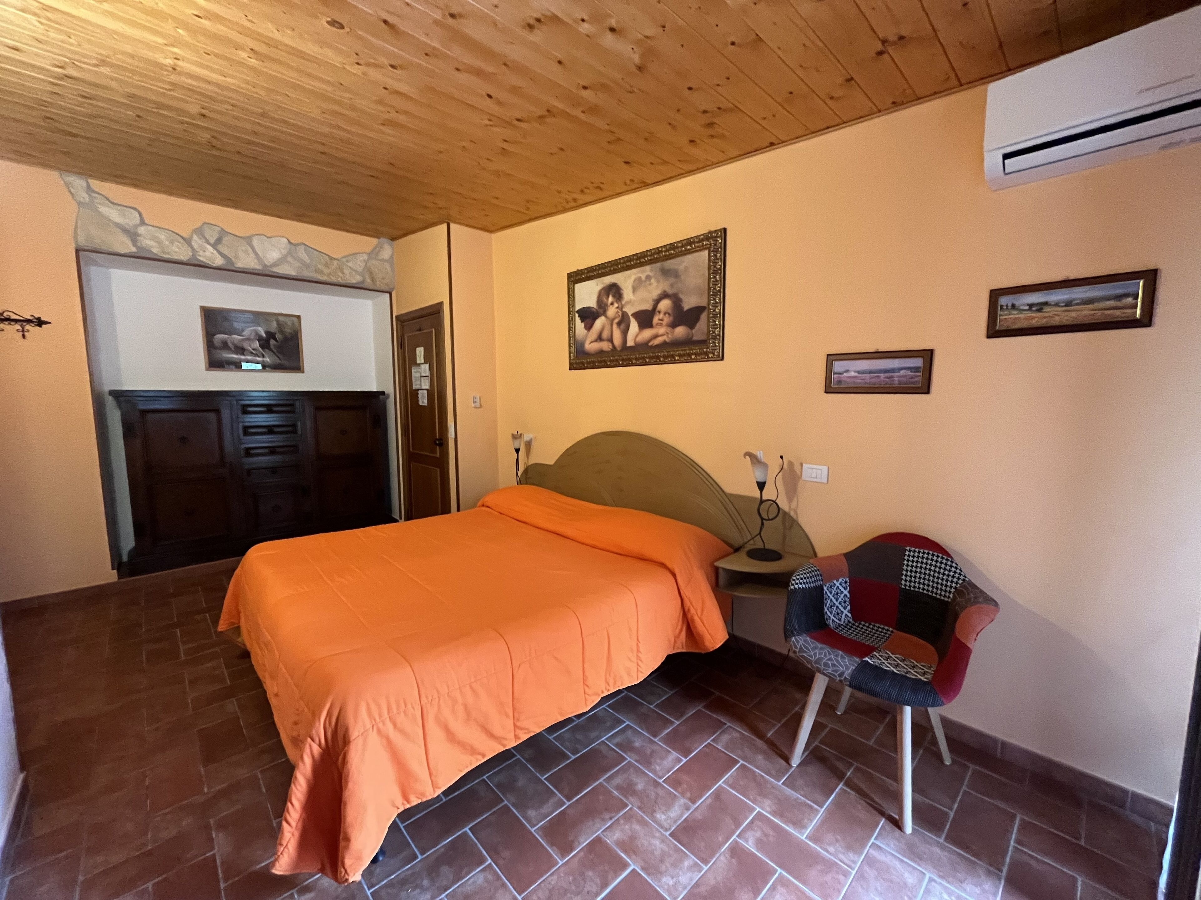Ein Schlafzimmer mit Bett, Sessel, Kommode und einem Bild an der Wand.