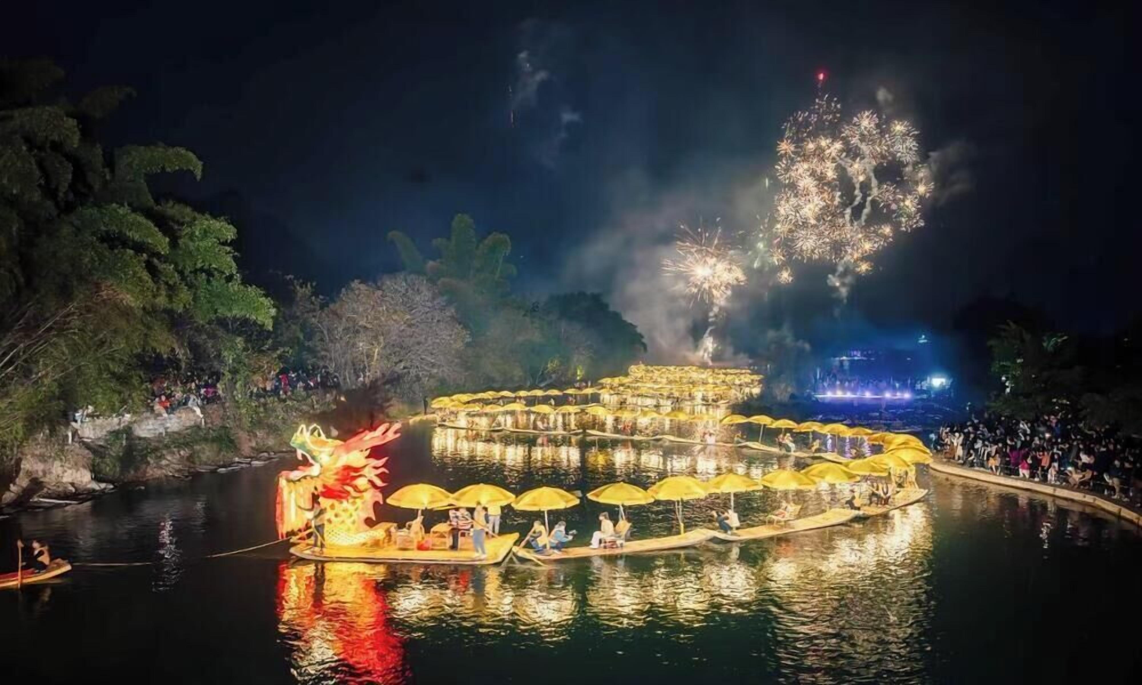 Escena nocturna al aire libre con un cuerpo de agua, barcos y una figura de dragón flotando.
