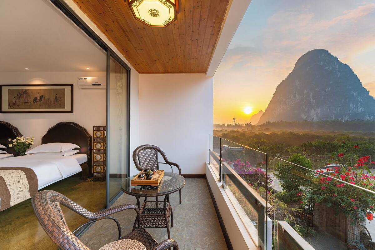 Une chambre d’hôtel avec un balcon, un lit, une table à manger et des chaises.