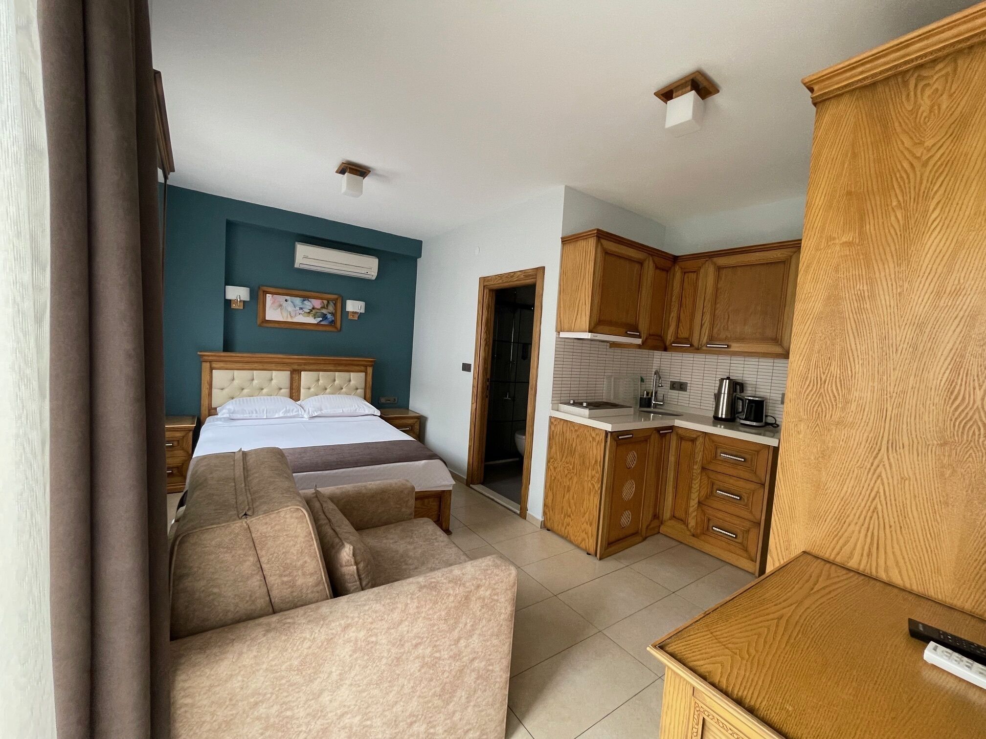 A bedroom with a bed, a sofa, and a kitchenette.