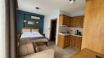 A bedroom with a bed, a sofa, and a kitchenette.