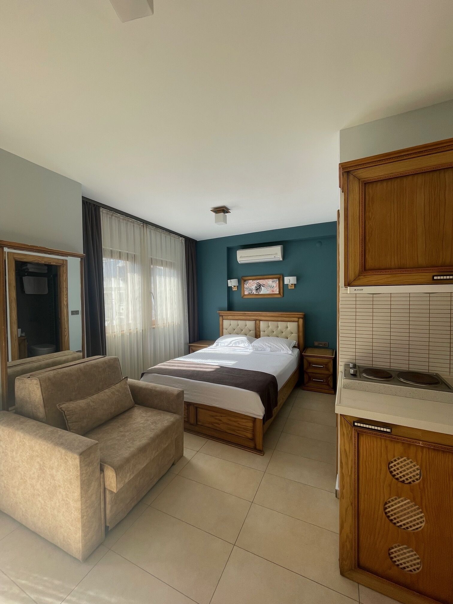 Una camera d'albergo con un letto, un divano, angolo cottura e una finestra con tende.