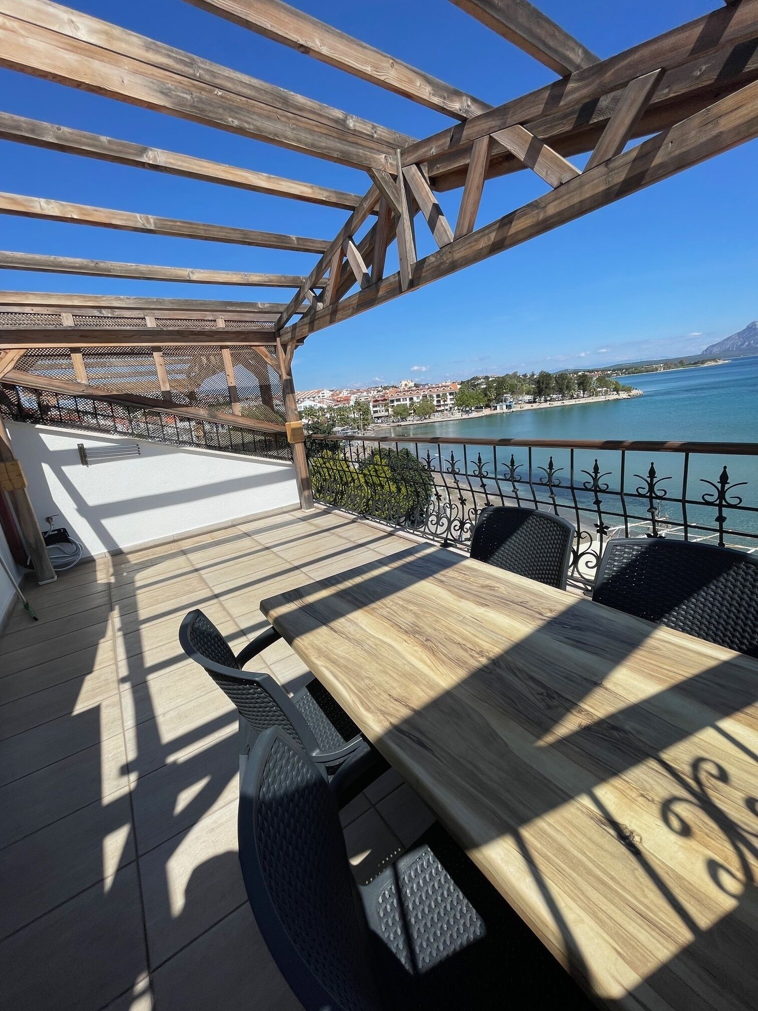 Un patio al aire libre con una pérgola de madera, una mesa y sillas.