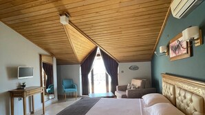 A bedroom with a wooden ceiling, a bed with a headboard, a desk, a chair, and a TV. - Veziroglu Apart (Datça)
