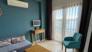 A living room with a sofa, a coffee table, a TV on a stand, and a chair. - Veziroglu Apart (Datça)