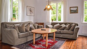 A cozy living room with two grey sofas, a wooden coffee table, and a red patterned rug.