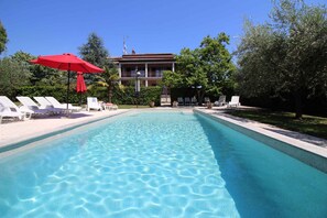 Relax by the serene pool surrounded by lush greenery and comfortable lounge chairs.