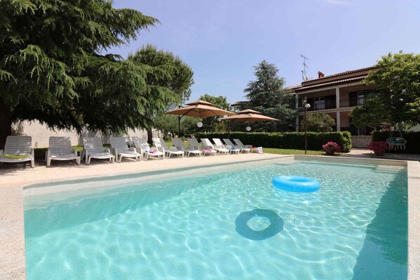 Relax by the serene pool surrounded by lush greenery and lounge chairs.