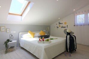 Relax in a serene bedroom with a skylight above the bed, a neatly made bed, and a cozy side table.