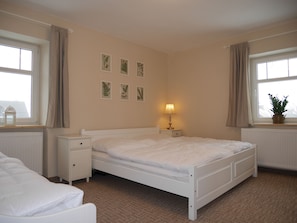 A bedroom with a single bed, a bedside table, a lamp, and a window with curtains.