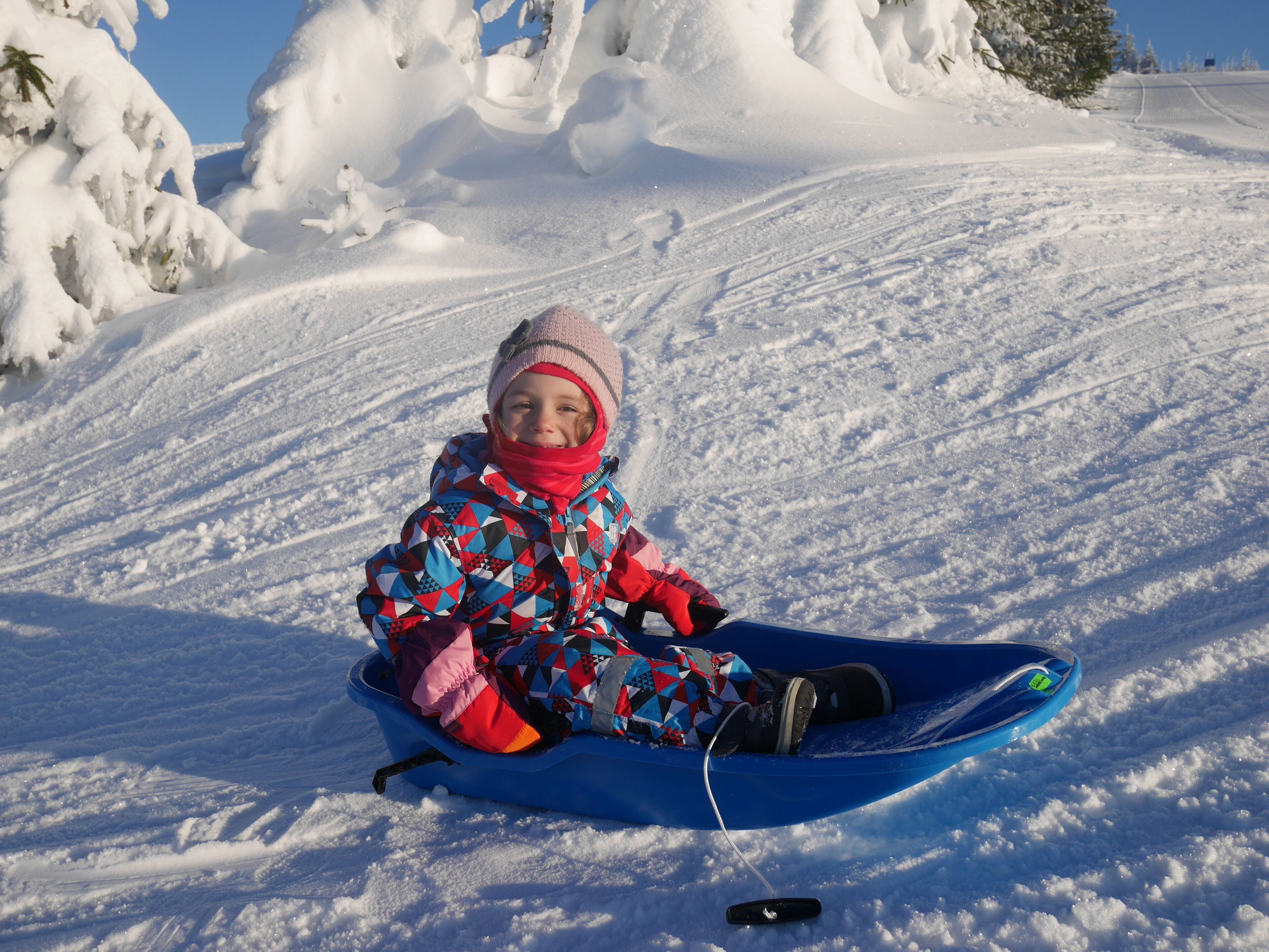 A child sledding down a snowy slope.