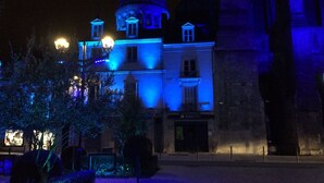 Un bâtiment historique doté d’un dôme imposant et d’une architecture classique, illuminé par un éclairage bleu.