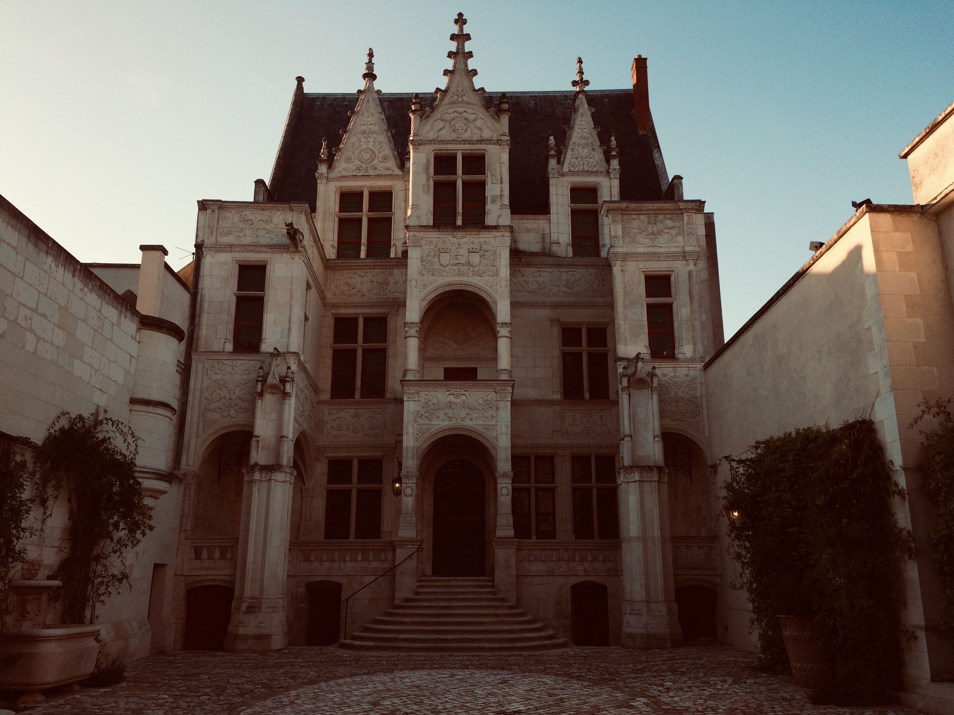 A historic building with a symmetrical facade, multiple windows, and a central entrance with a staircase leading up to it.