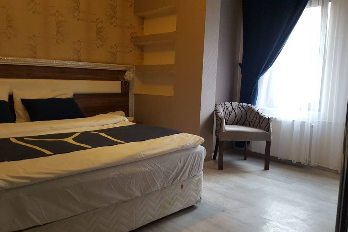 Een hotelkamer met een bed, een stoel en een raam met gordijnen.