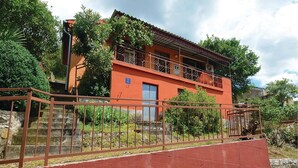 A two-story building with a red facade, a blue door, and a balcony. - 2 bedroom cozy home in Trget (Trget)