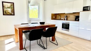 Una cocina moderna con armarios blancos, horno empotrado y microondas.