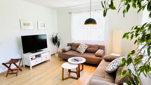 A living room with a flat-screen TV, a sofa, a coffee table, and a potted plant. - Apartment with a large terrace (Altmünster)